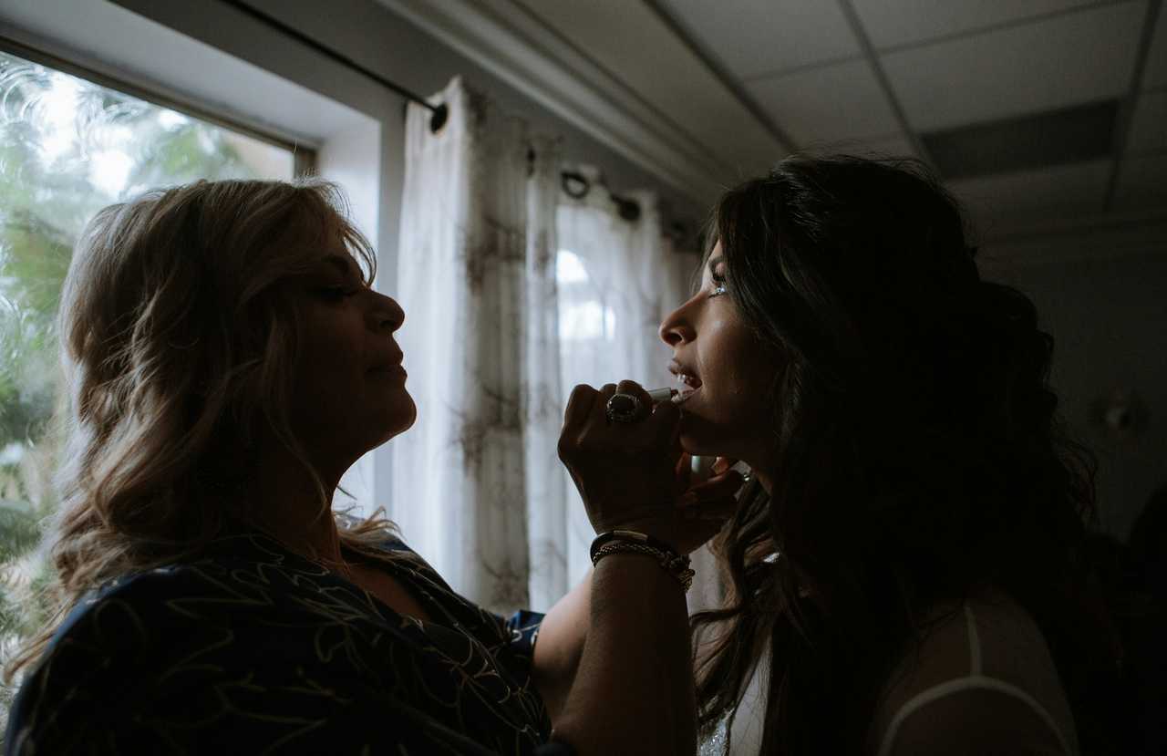 mother doing daughter make up in a dark room