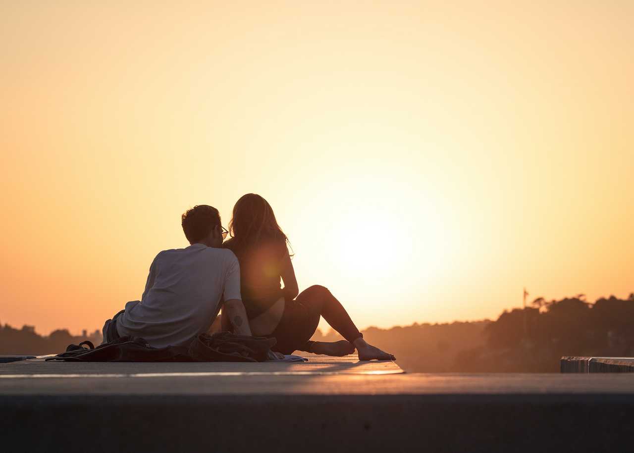 boyfriend and girlfriend seated looking the sun down saying love messages for him