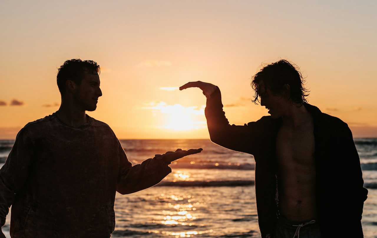 friends about to shake hand after saying short positive messages to each other in a beach during the sunset