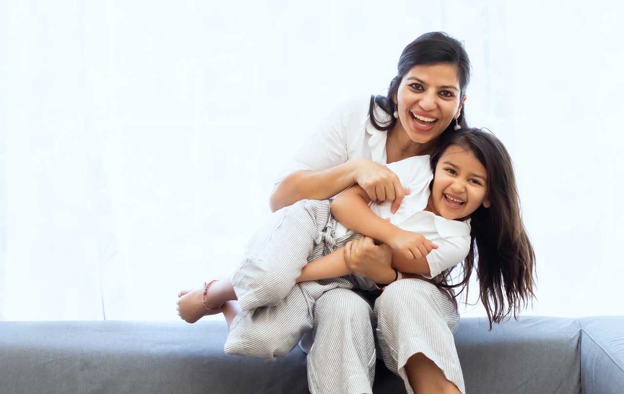 mother and daughter wearing white and hugging laughing sending happy mother's day