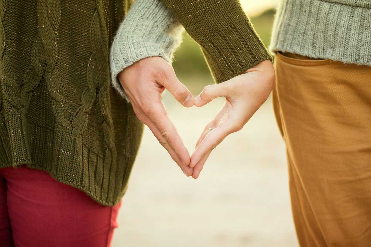 detail of two persons making a heart shape with their hands in the height of their waist and sending good morning sweetheart messages and greetings
