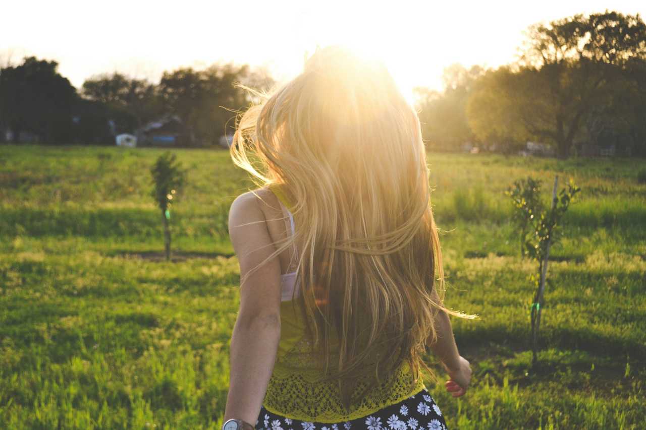 woman walking into a grass field under the morning sun after receiving good morning messages for her