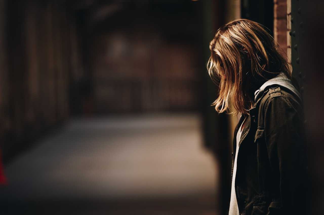 woman in a dark corner sad for sending a break up message