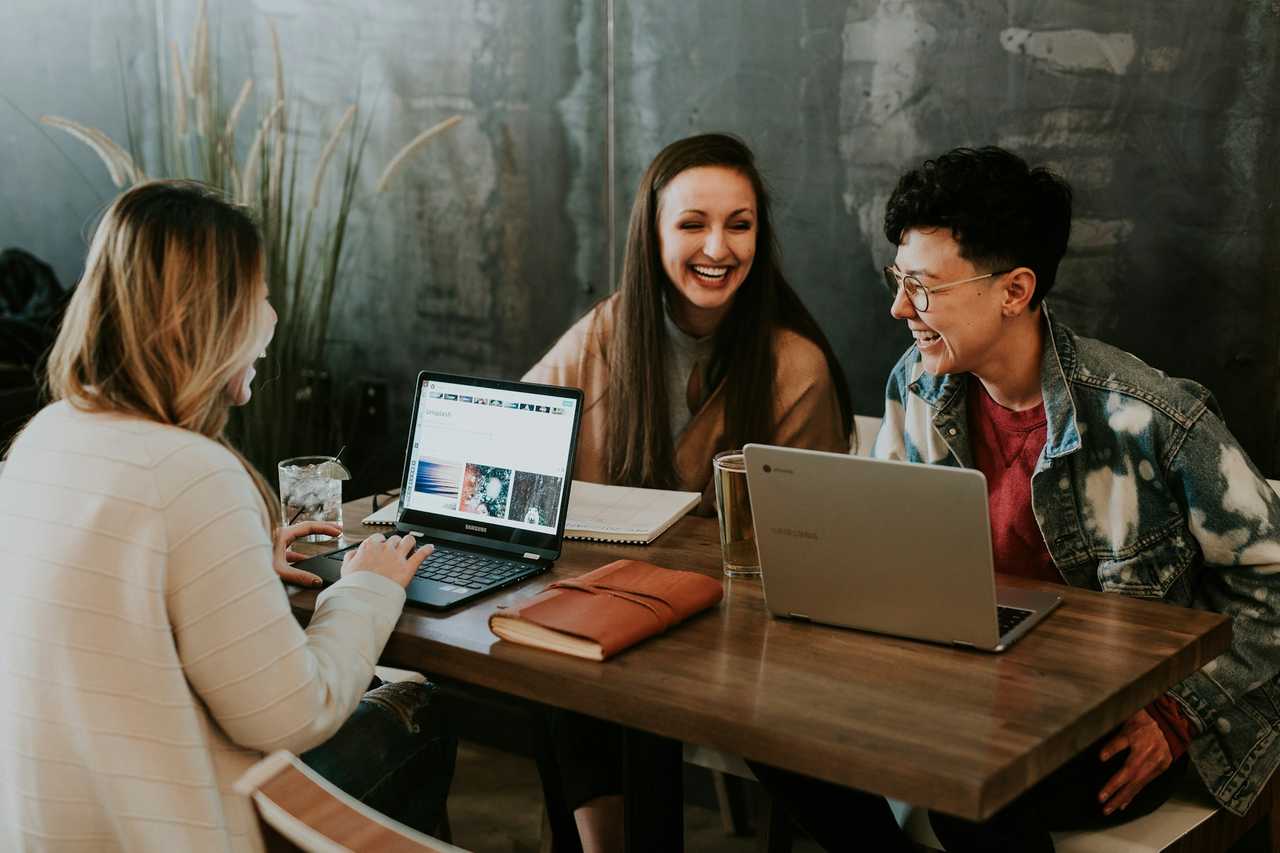 people cheering and laughing on a table with computers for sending ai messages generated by the everything else ai generator