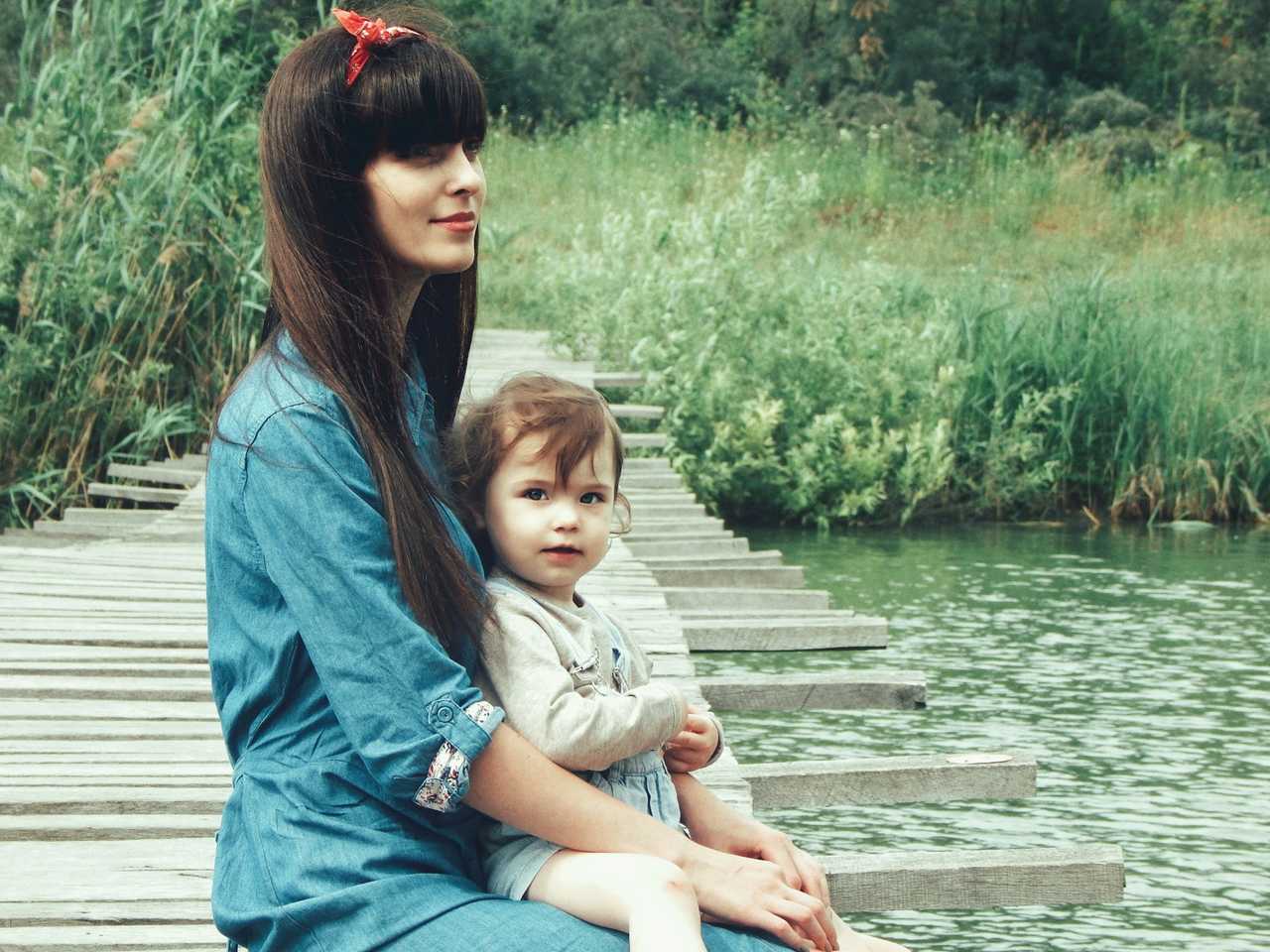 woman holding baby daughter by a lake