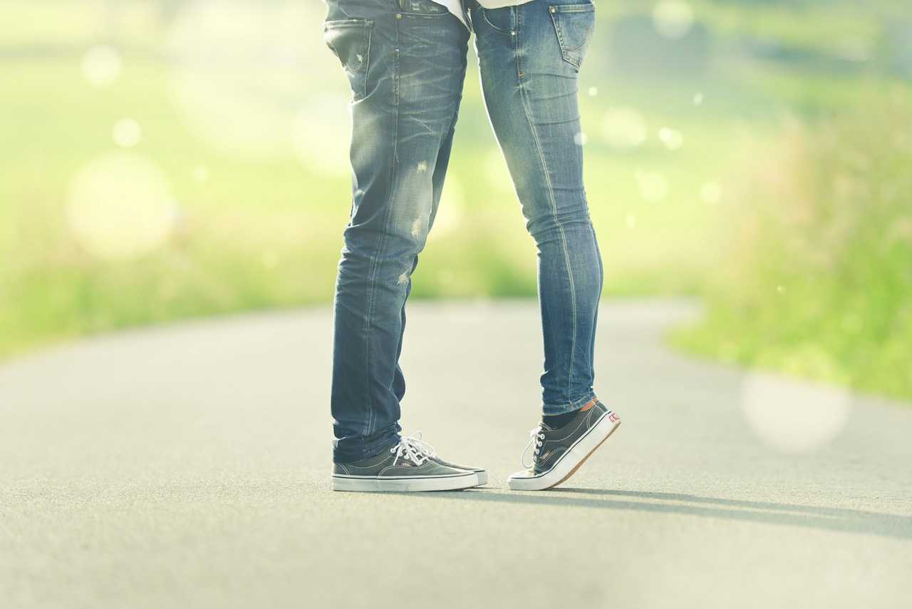 two person kissing for the first time standing on a walk way in a part