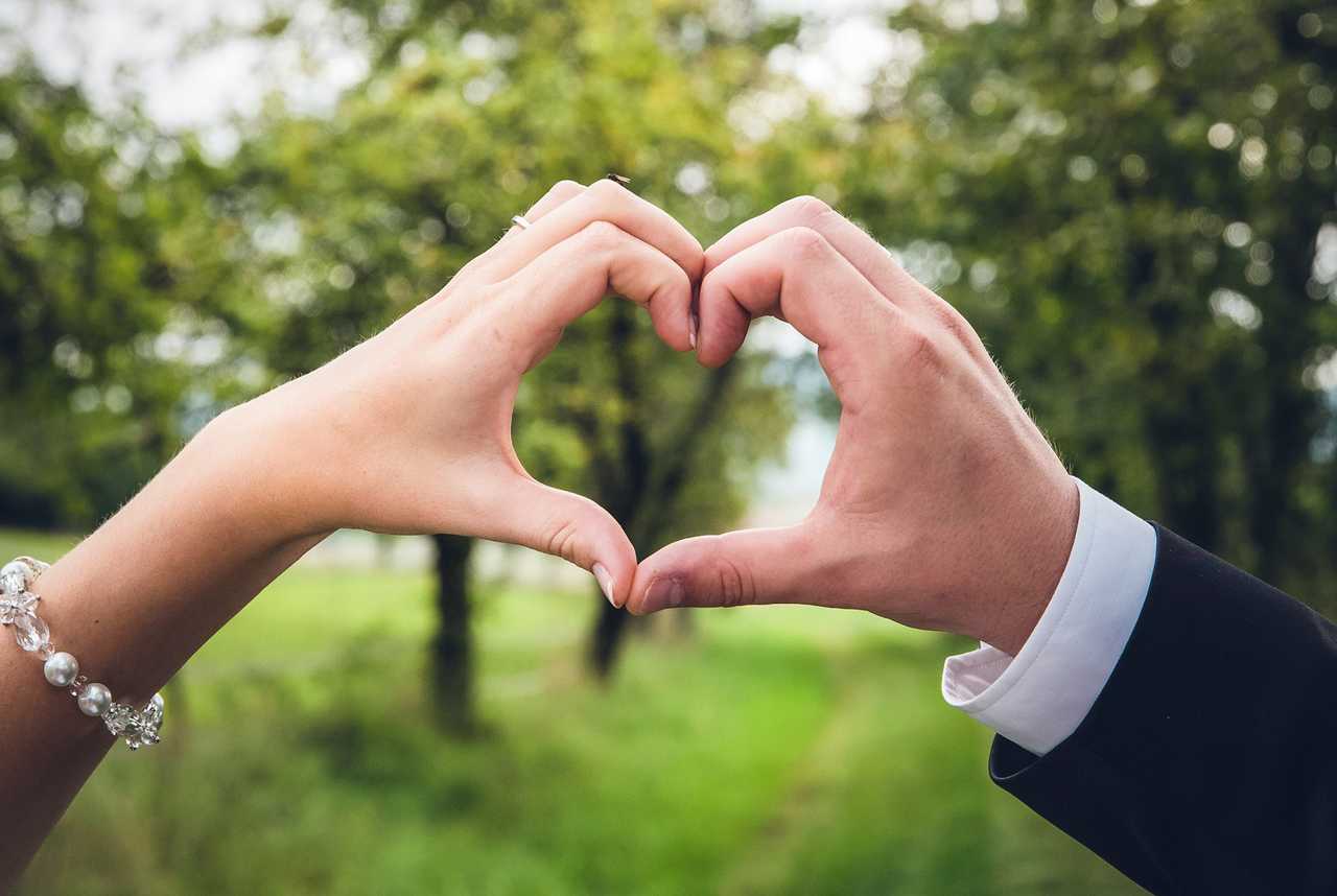 hands from a couple making a heart shape together after sending ai generated happy anniversay messages