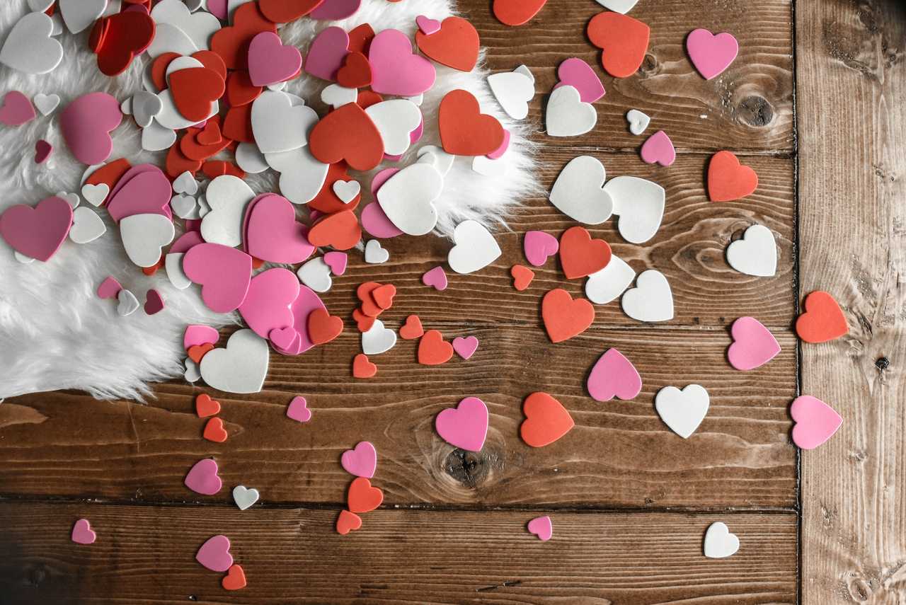 paper hearts cut out and spread over a wooden flor to use with valentine's days quotes for her