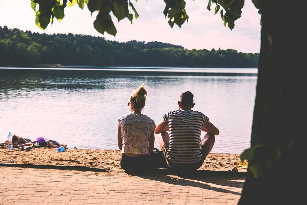 couple seated by a lake in a park as a first date talking about their favorite places
