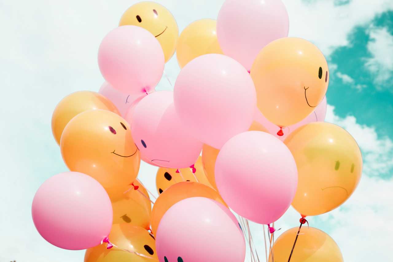 pink and yellow balloons under a blue sky to be used in a birthday invitation message