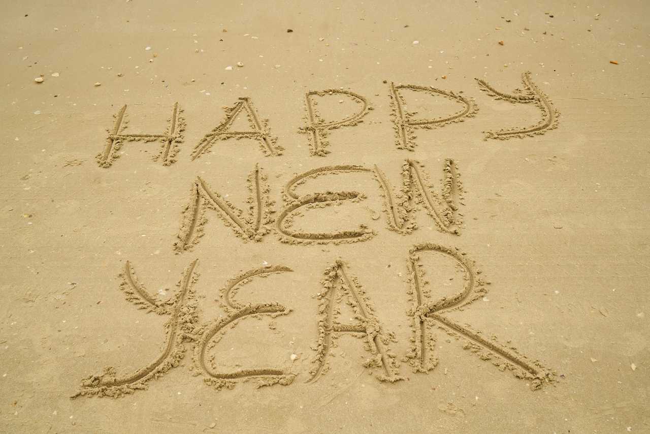 happy new year wish written in the sand