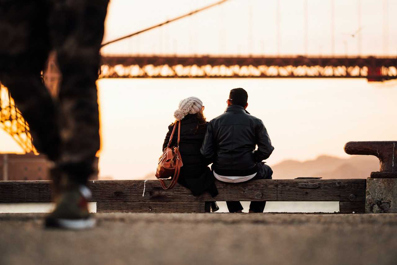 couple seated by a river watching the landscape on their first date and not kissing