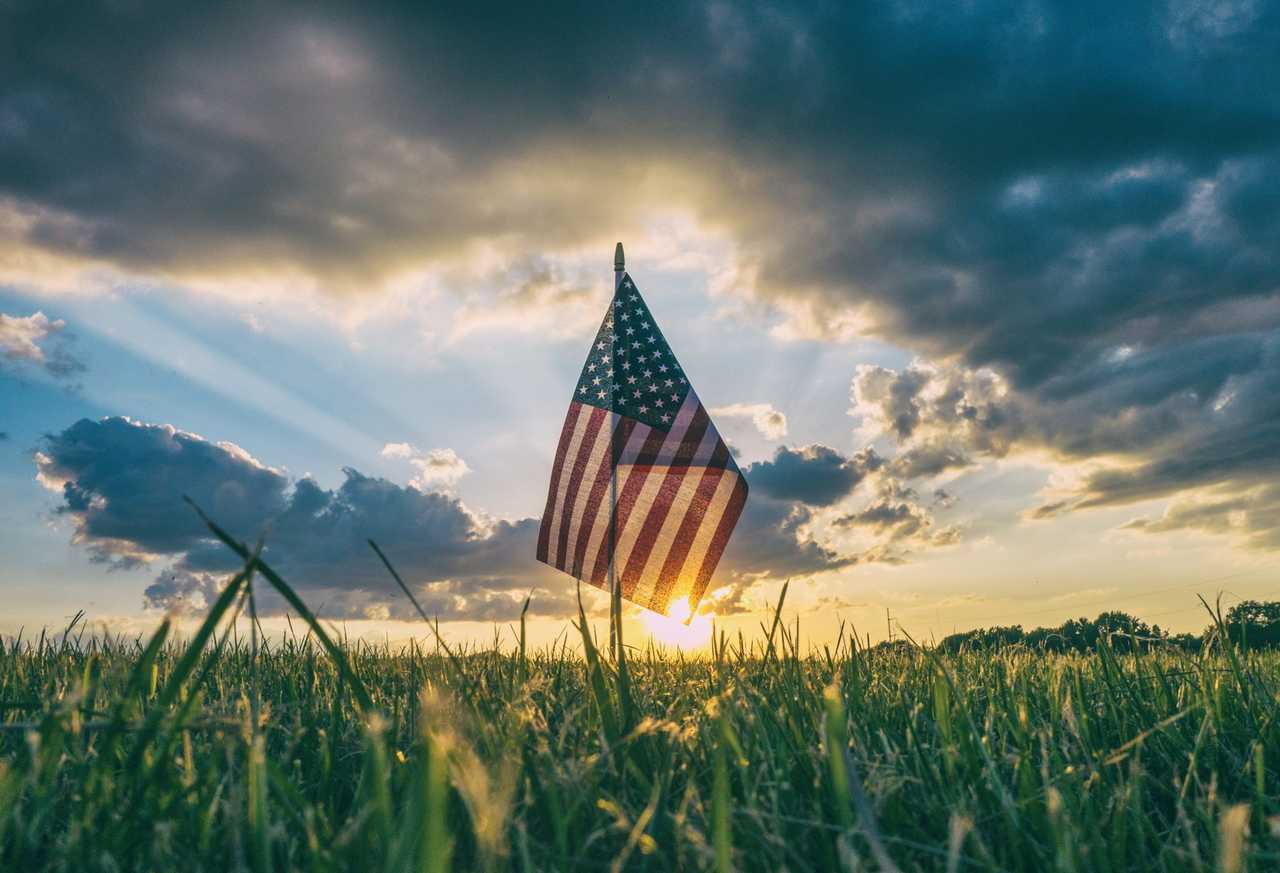US flag in a field under a cloudy sky for independence day patriotic quotes