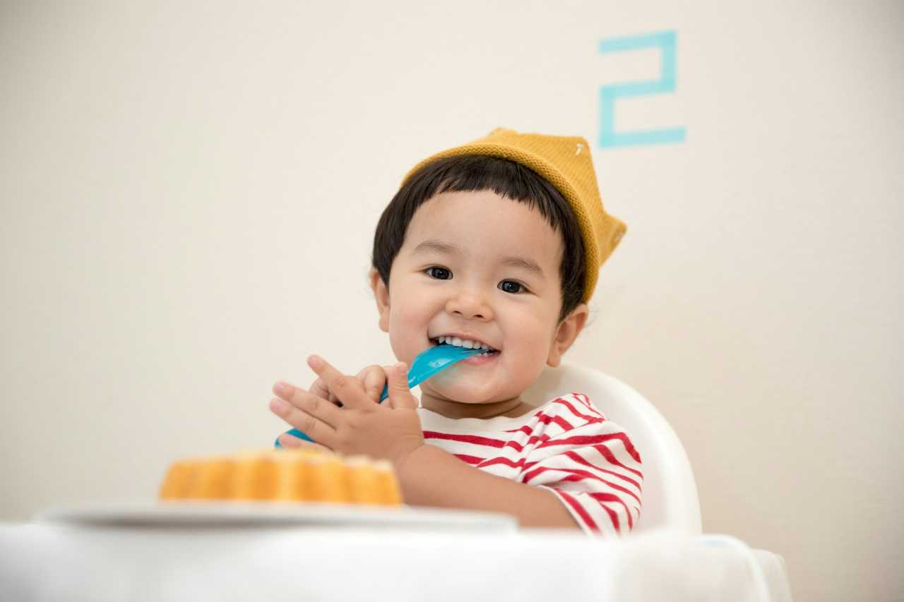 kid smiling behind a small cake in his birthday for invitation message