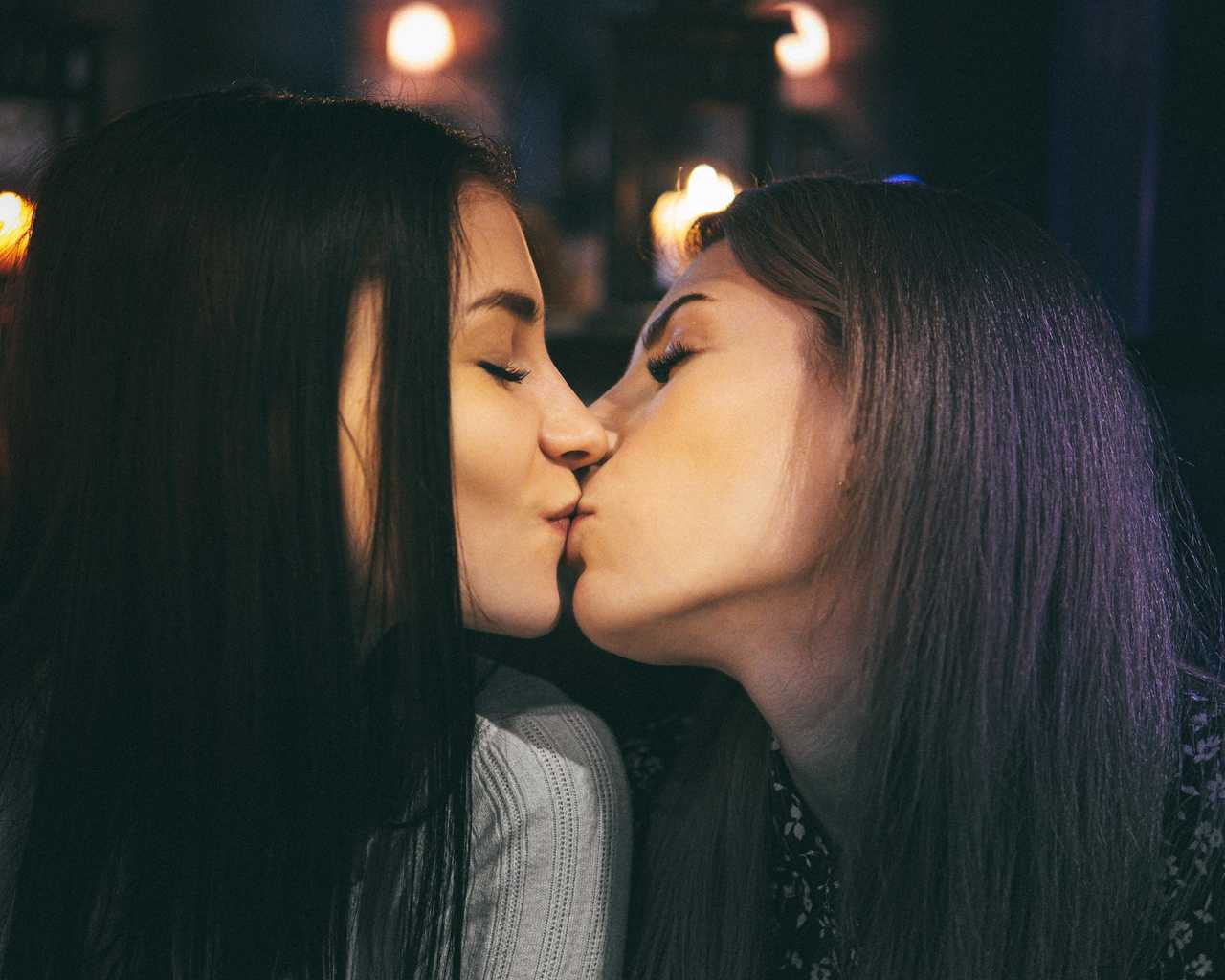 two long-haired women at night giving their first kiss