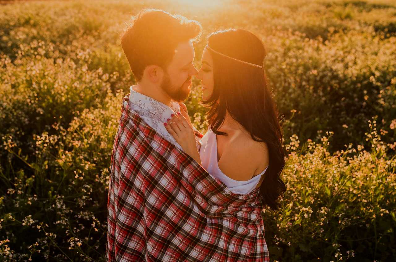 couple kissing for the first time in a field with flower in the golden hour