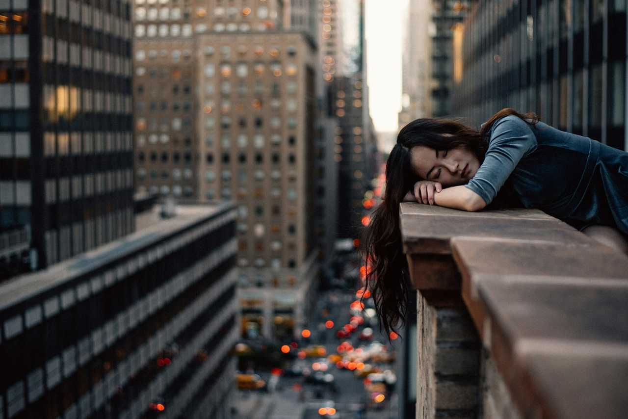 woman leaning in the edge of a building and resting her head while the sun is rising in the morning and getting morning wishes for her