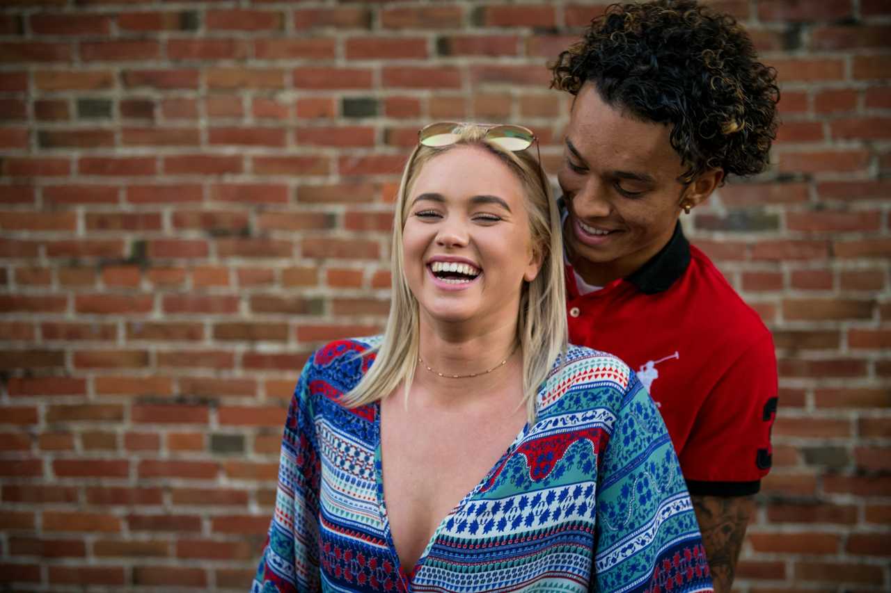 couple laughing with i love you messages brick wall in the background