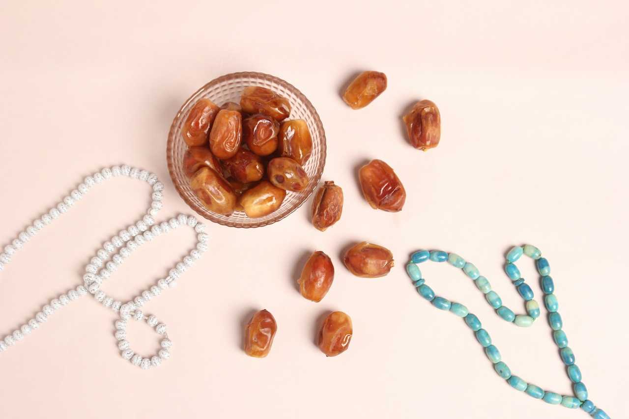 glass bowl filled with nuts next to a beaded necklace photo for saying happy ramadan to muslim friends