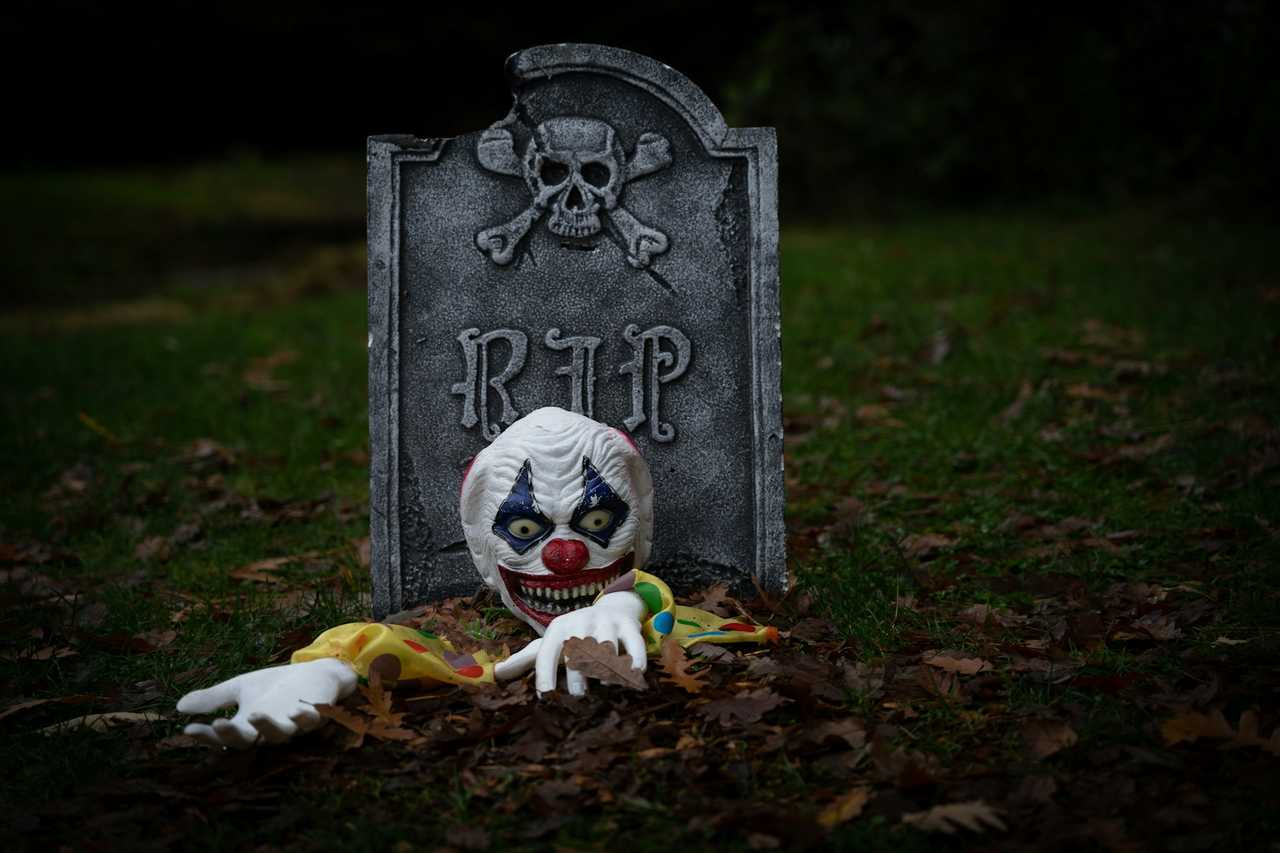 halloween prop tombstone with rip saying and a zombie doll raising from the grave