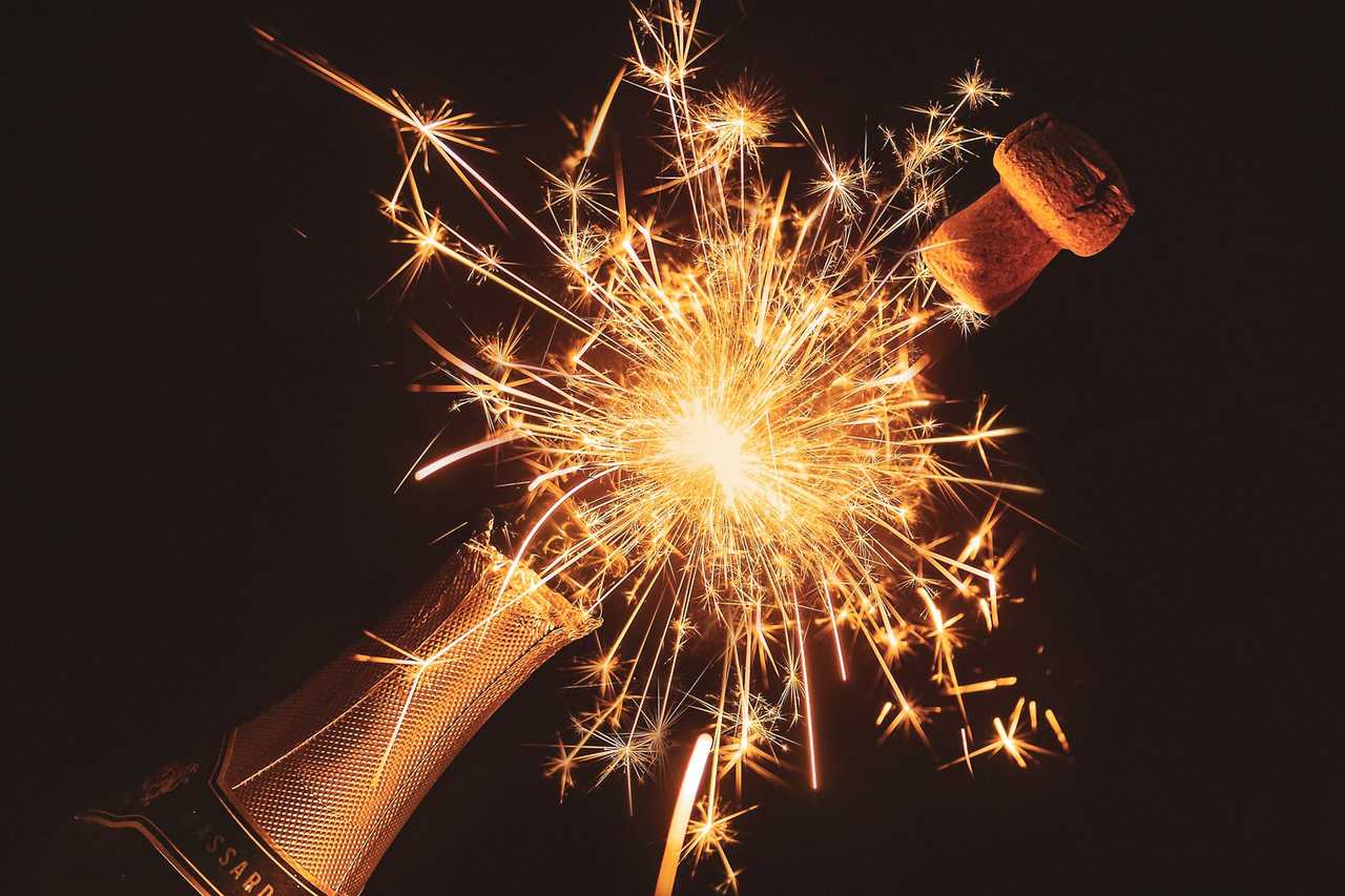 champagne bottle with firework display behind to send with new year messages