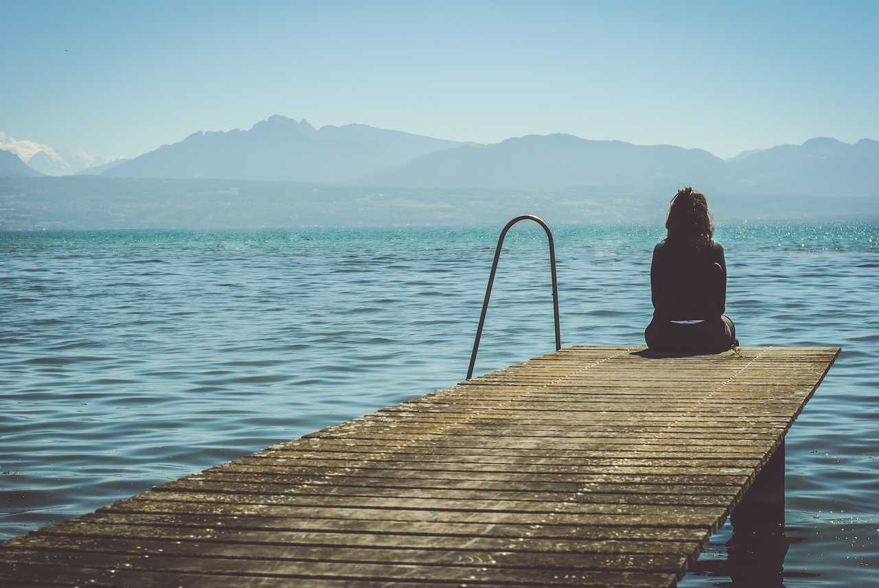 woman sitting in a dock by the sea sad because she ended a relationship with break up messages