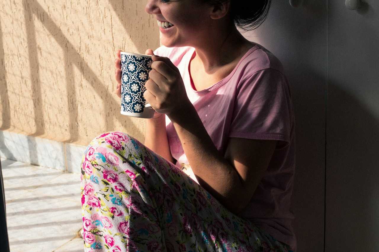 woman in her PJs holding a cup of coffee laughing getting good morning messages for her