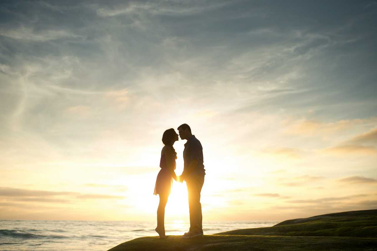 couple kissing for the first time by the sun during the sundown