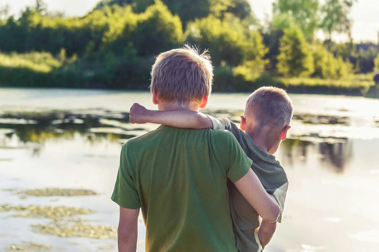 brothers holding each others in front of a lake for i miss you messages