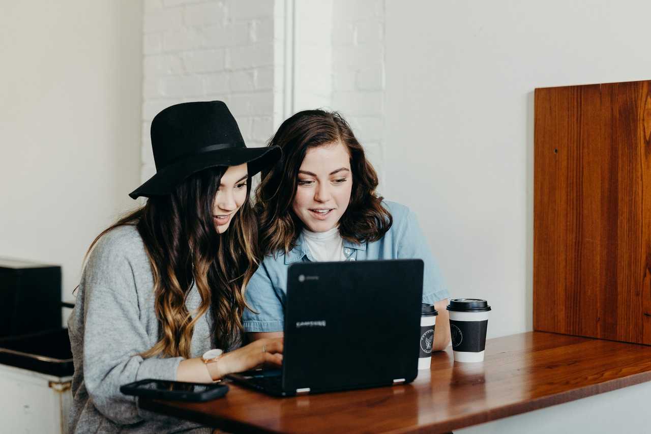 two friends in a table sending ai generated messages by their computer