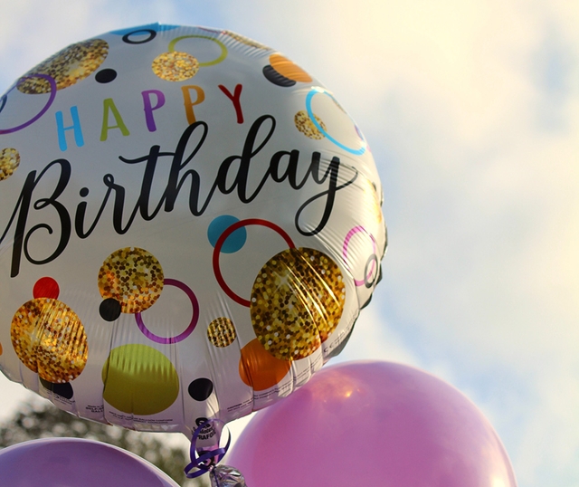 happy birthday balloon with a cloudy sky in the background