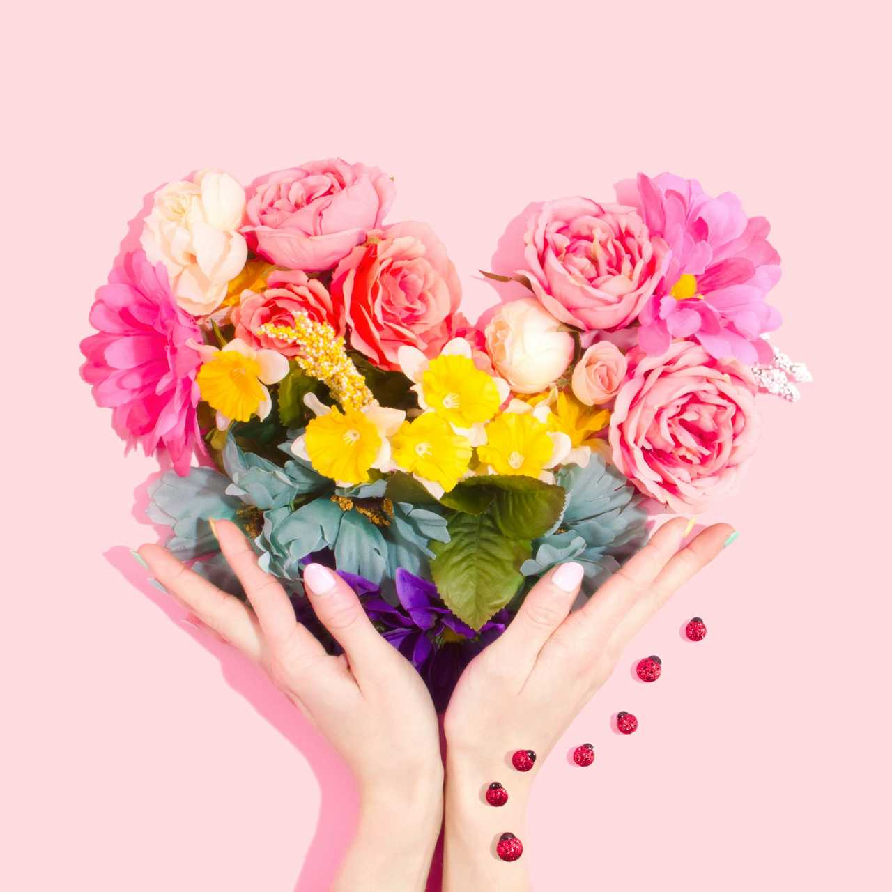 hands holding a hear shaped array of flowers in valentine's day