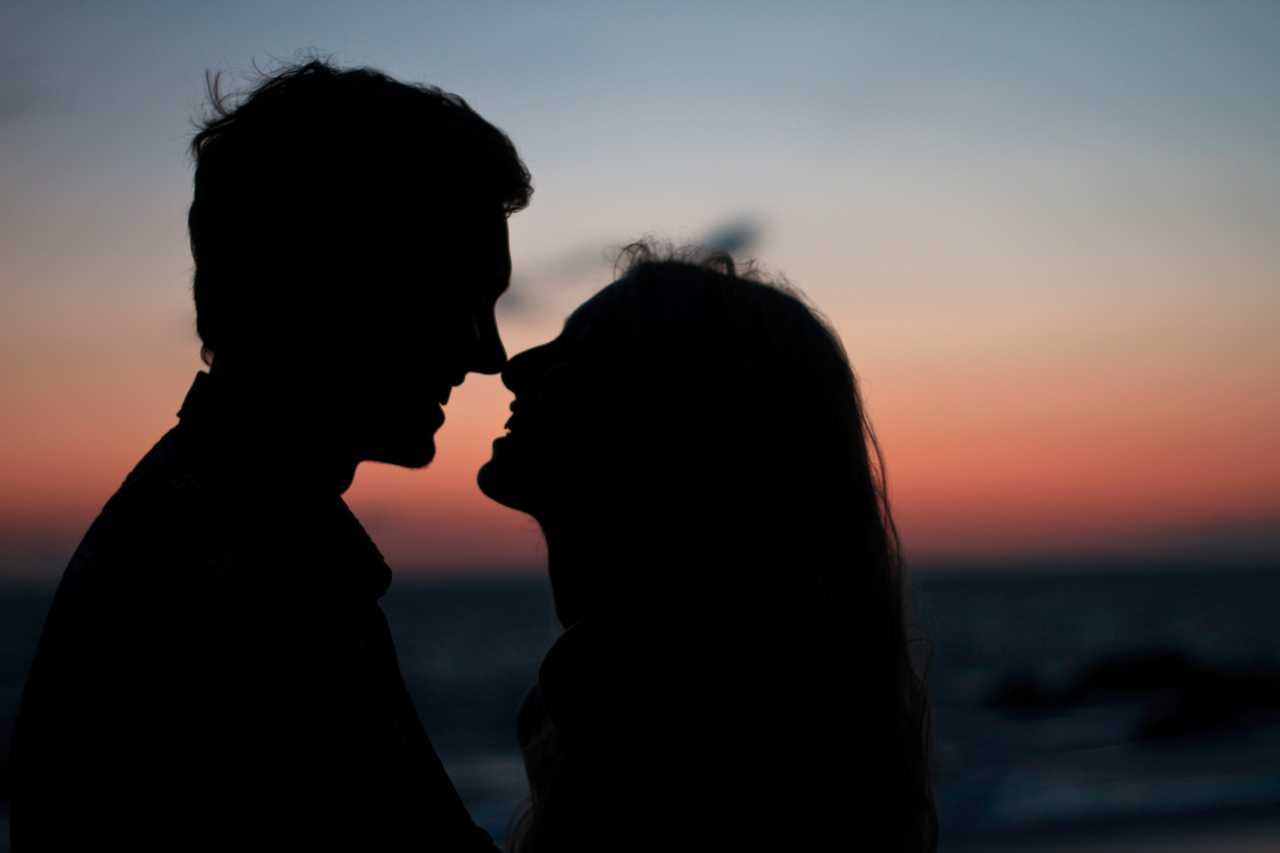 couple kissing for the first time by the sea in the sundown