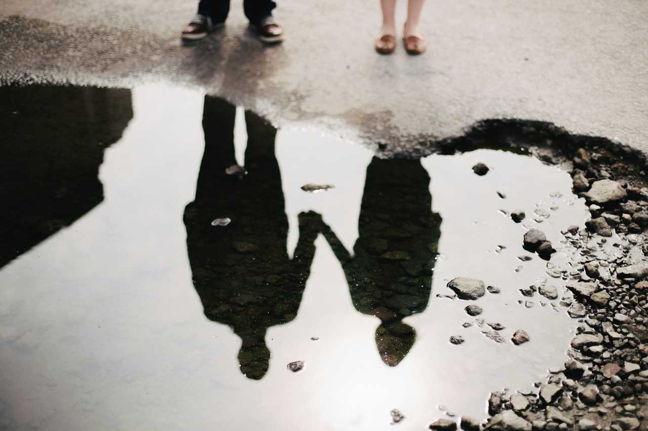 couple standing by a puddle where we can see their reflection on Valentine's Day after sending messages for boyfriend 