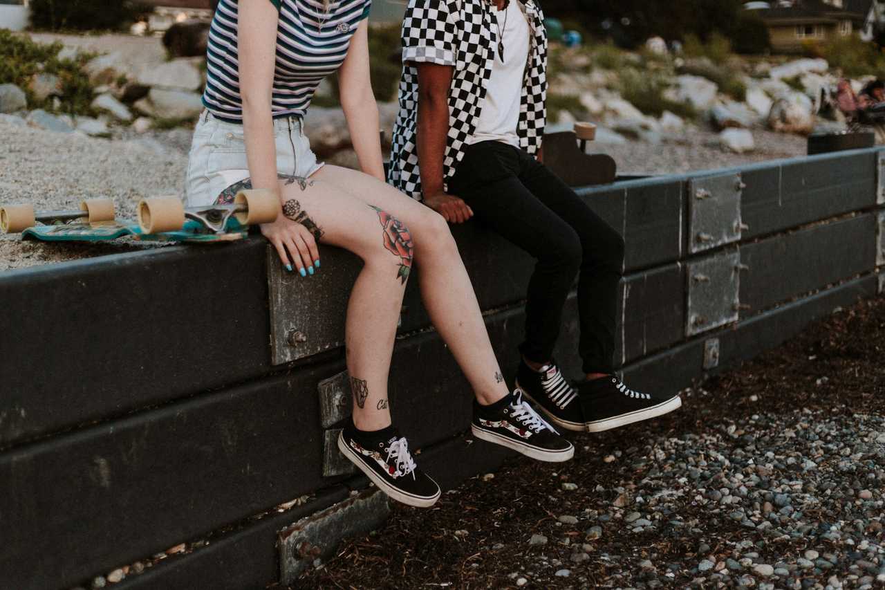 couple seating in a low wall side by side in their first date talking about food and hobbies