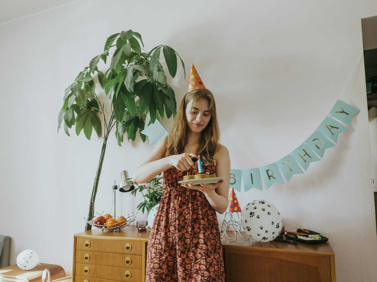 young woman lighting candle on her birthday on a living room with birthday wishes for sister written behind