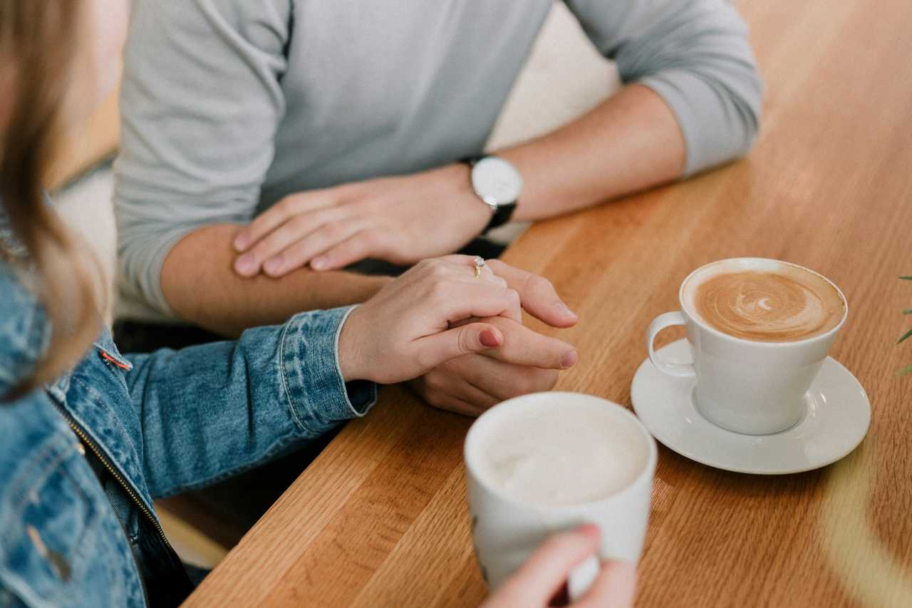 couple on a date in valentine's day detail of them holding hands and coffee