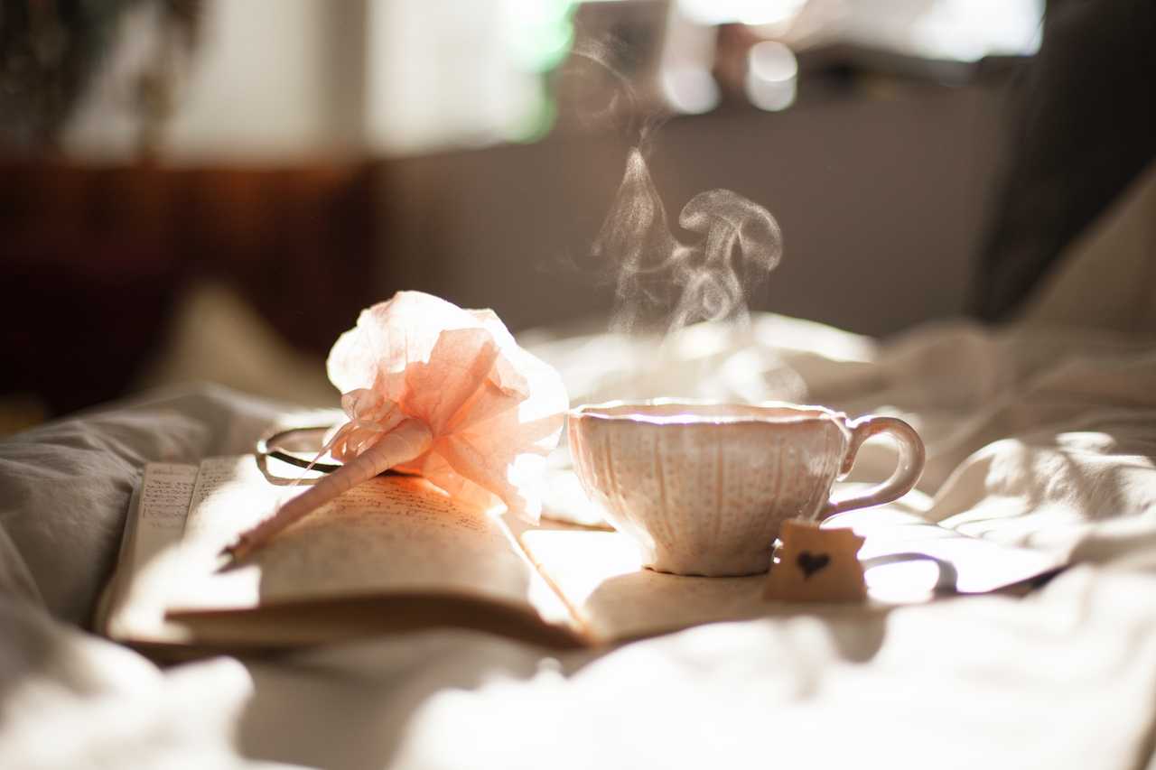 cup of coffee and paper flower over a book in a bad in the morning for ai generated good day wishes